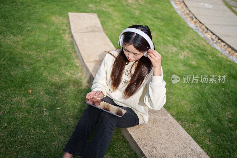 年轻女子在公园里戴着耳机