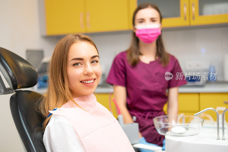 快乐的年轻女病人微笑着坐在牙科诊所的医疗椅上。