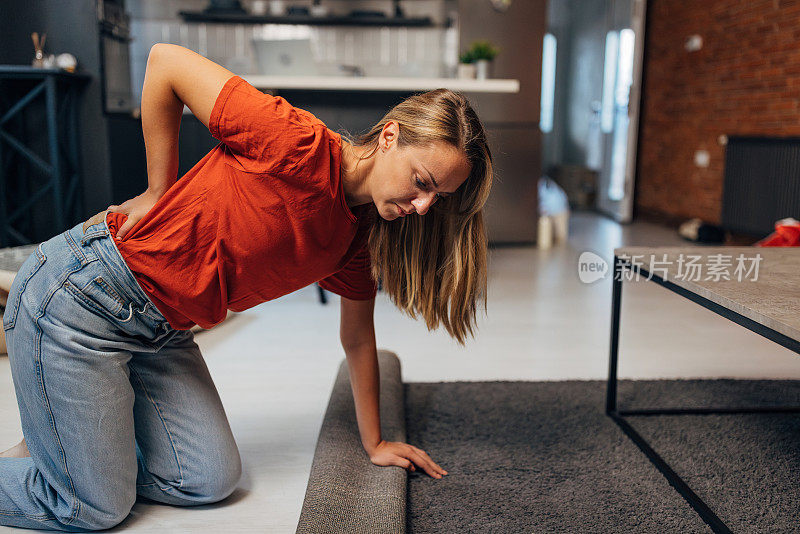 一个女人在打扫房子的时候感到背部疼痛，就把地毯拿去洗