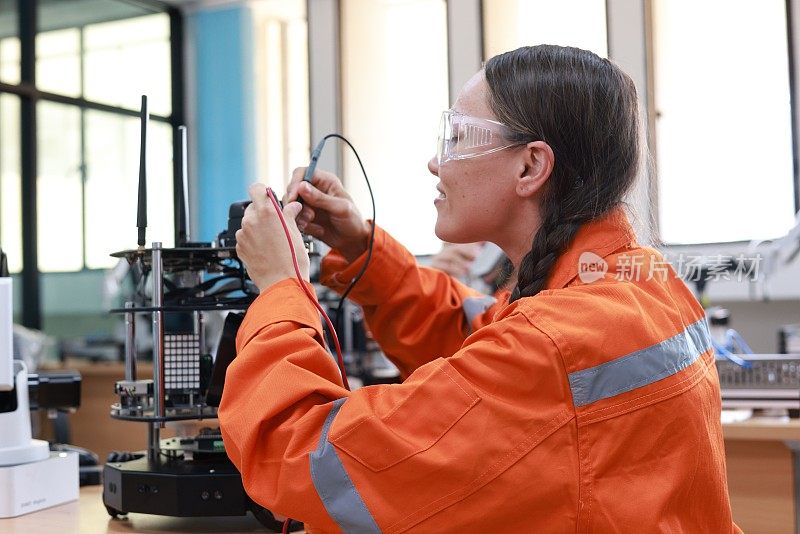 在工厂里，一位女工业工程师正在检查一台带有机械臂和气缸的工程自动化机器。