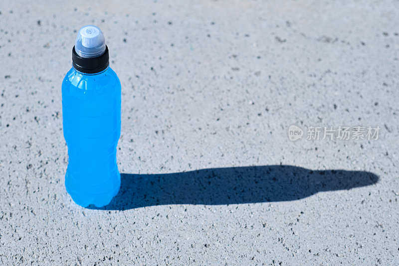 一个标准的透明塑料瓶PET与蓝色能量饮料在阳光明媚的日子里户外的一般镜头
