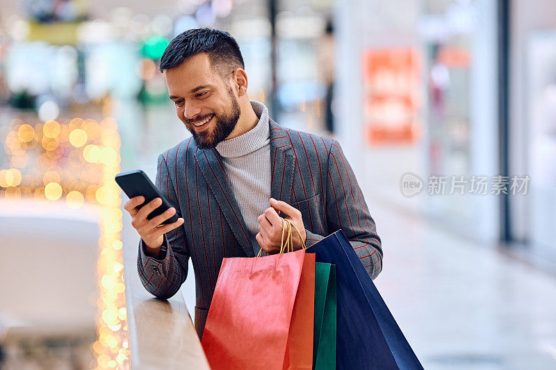 快乐的男人一边在商场购物一边发短信。