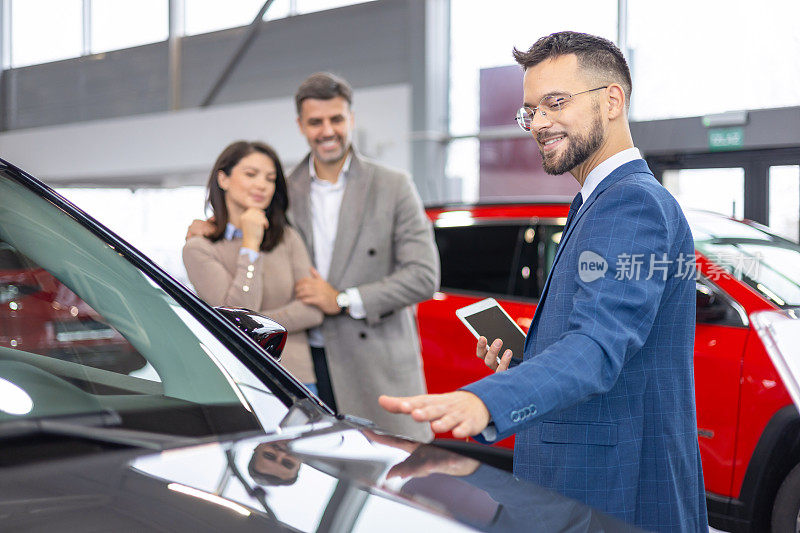 三个人在汽车经销店的陈列室里检查汽车