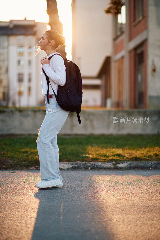 一个美丽的欧洲少女，在夕阳下放学回家，背着她的背包
