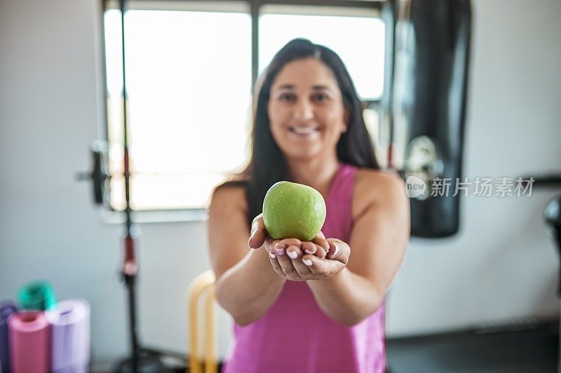 在家庭健身房里，女人伸出青苹果的手的特写