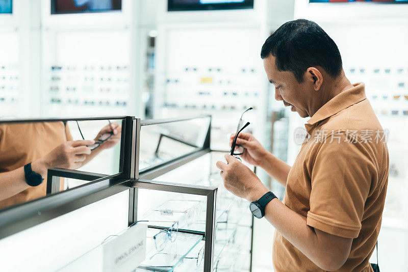 一名男子在眼镜店买眼镜并试戴一副——视力概念