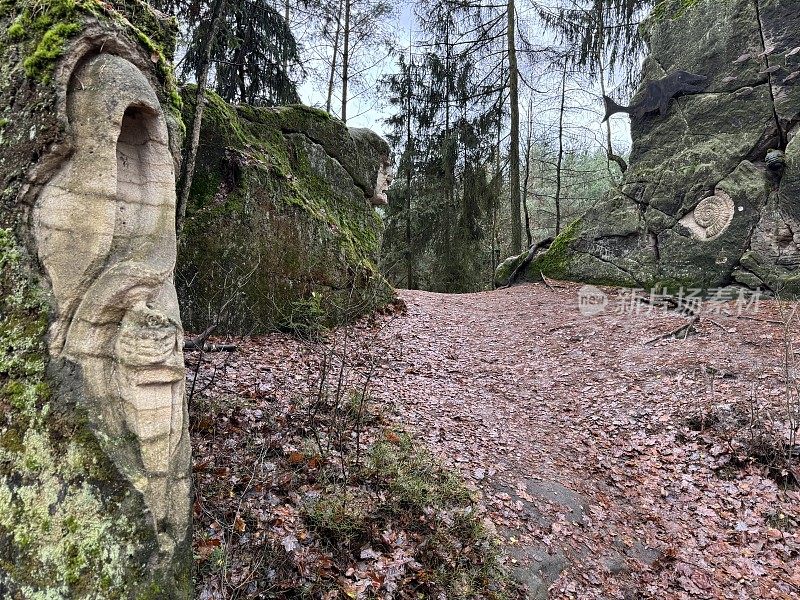 在捷克共和国波希米亚的一条森林步道上，雕刻在岩石上的令人毛骨悚然的恐怖雕塑