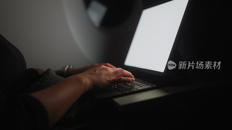 商务旅行时在飞机上用笔记本电脑或平板电脑工作的女商人