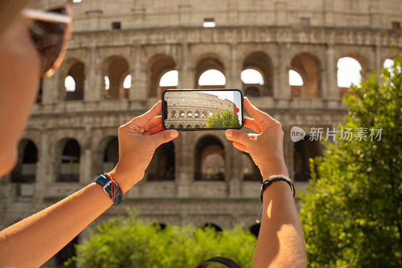 在意大利罗马的斗兽场圆形剧场，一名妇女用智能手机拍照
