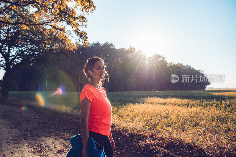 女运动员站在阳光明媚的秋景中