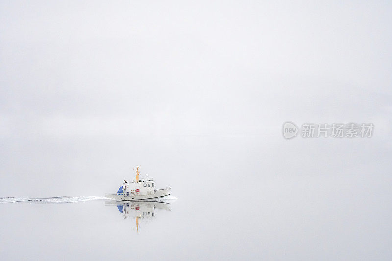 挪威冬天的早晨，在一个多雾的峡湾上的一艘小船