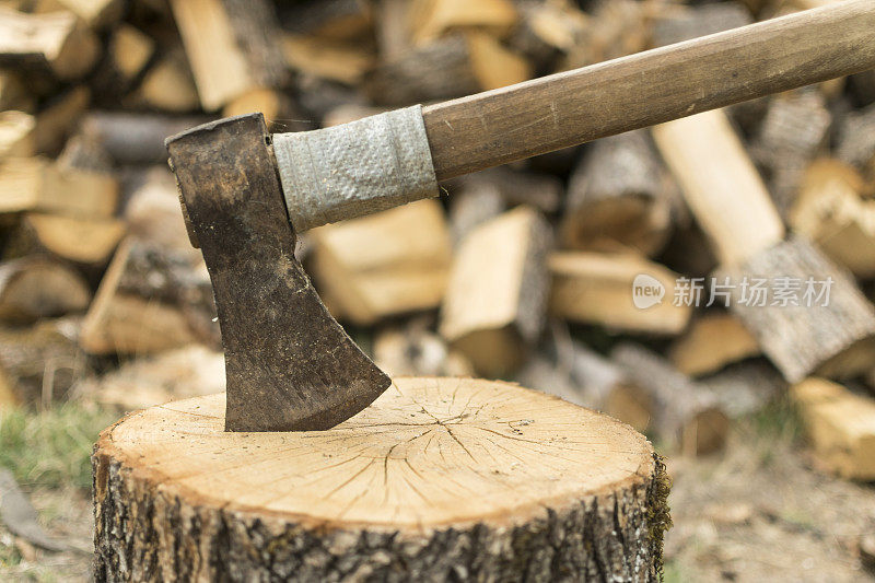 一把斧头卡在一堆木头前面的一根圆木上。