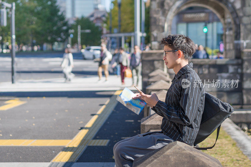 年轻的亚洲男子和日本朋友寻找旅游地点使用手机和花时间在亚洲旅行