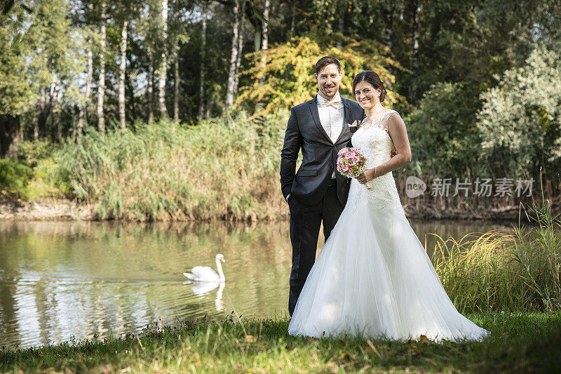 刚刚结婚的新娘和新郎站在湖边
