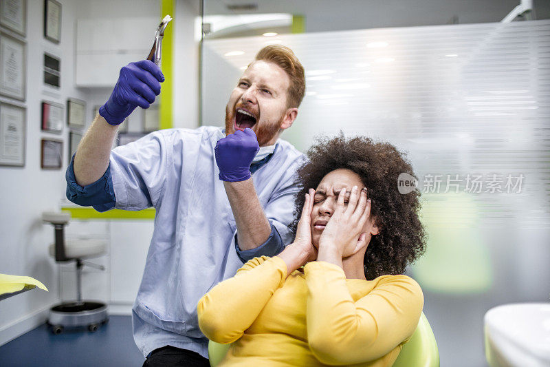 牙医得意地举着从饱受折磨的病人身上取下的一颗牙