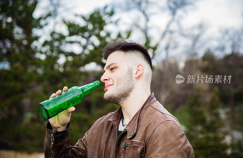 一个年轻人在户外拿着啤酒瓶