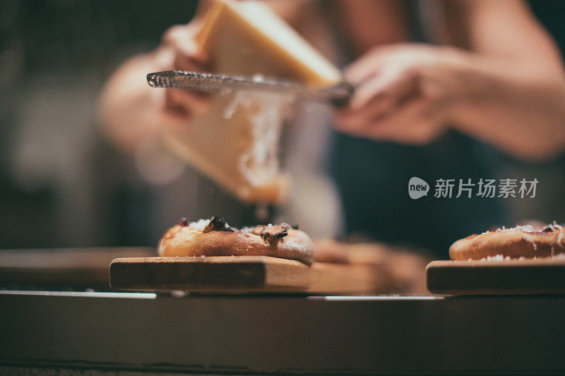 厨师将帕尔马干酪铺在意大利披萨上