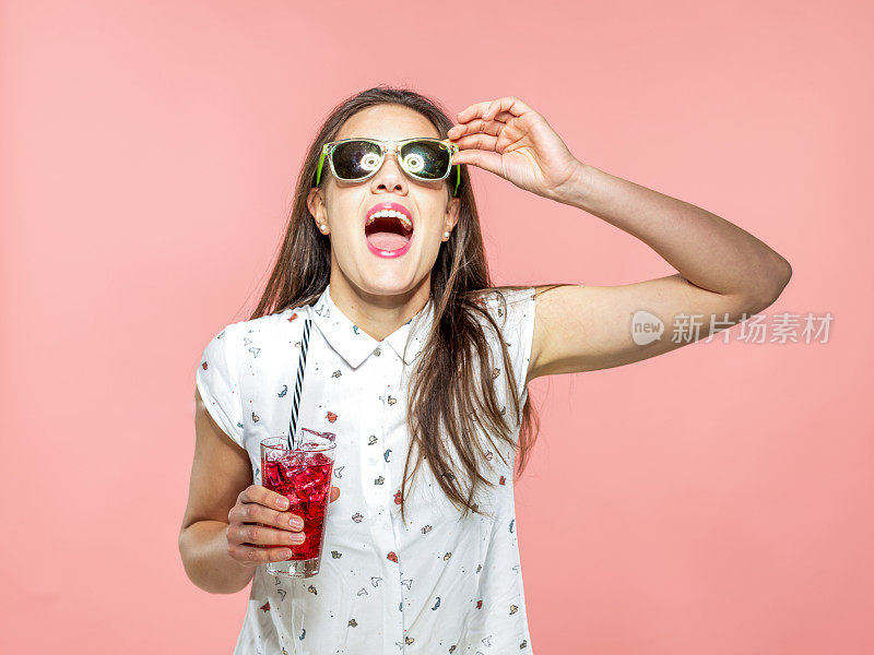 酷酷的年轻女人戴着太阳镜享受清凉的冰茶