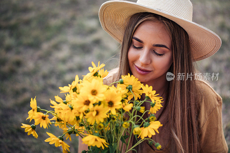 可爱的年轻女人闻着黄花