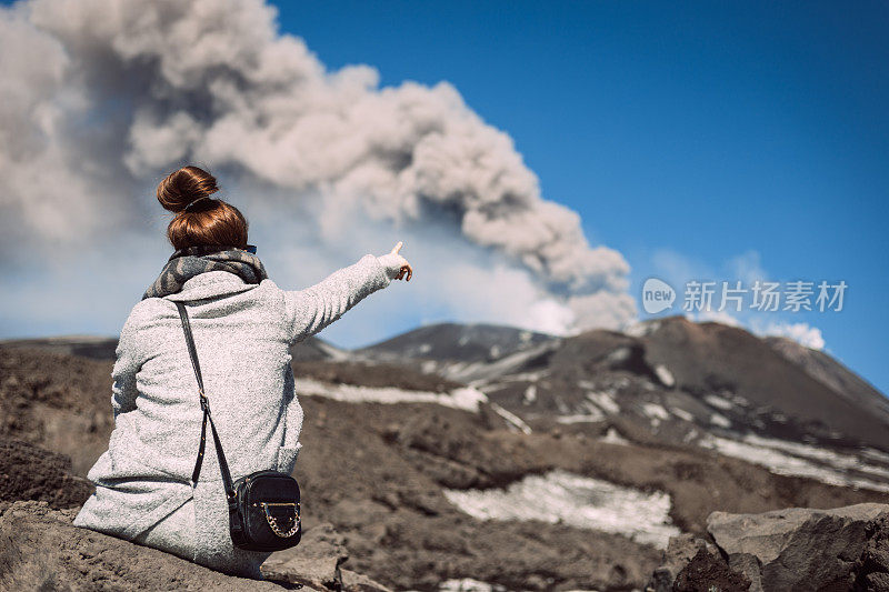 年轻女子指着活跃的埃特纳火山