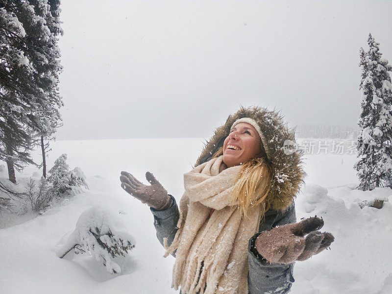 在冬日仙境里，年轻女子看着雪花从天而降