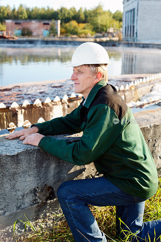 建筑工人戴着白色安全帽靠近污水处理池