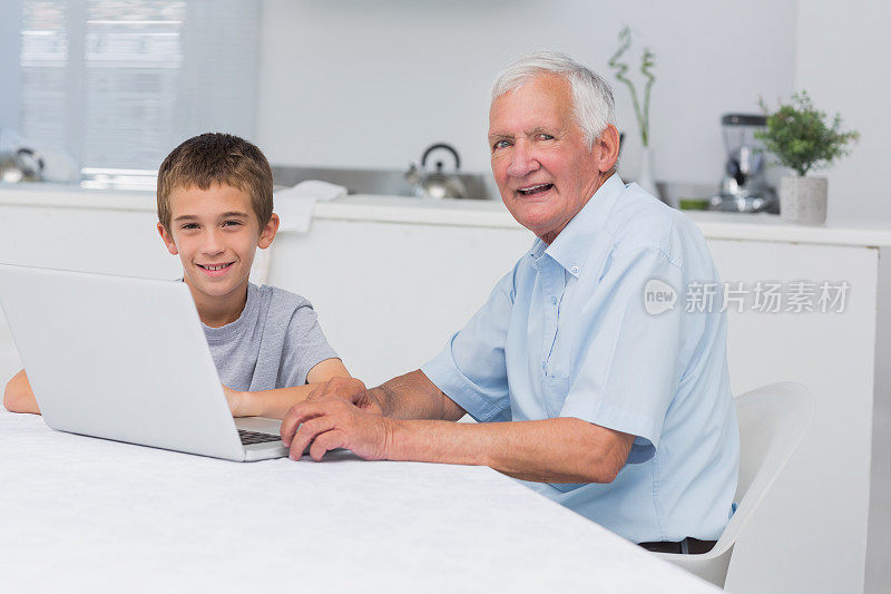 带着笔记本电脑微笑的爷爷和孙子