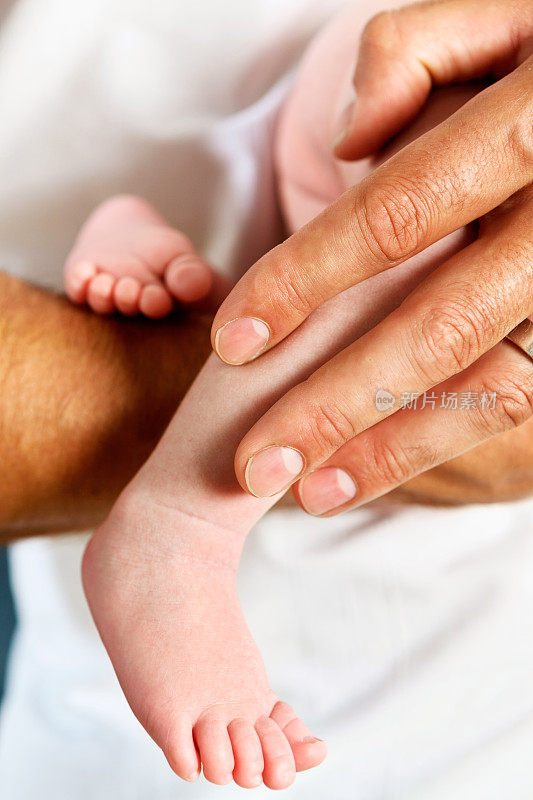 刚出生的婴儿的脚被男性的手抱着