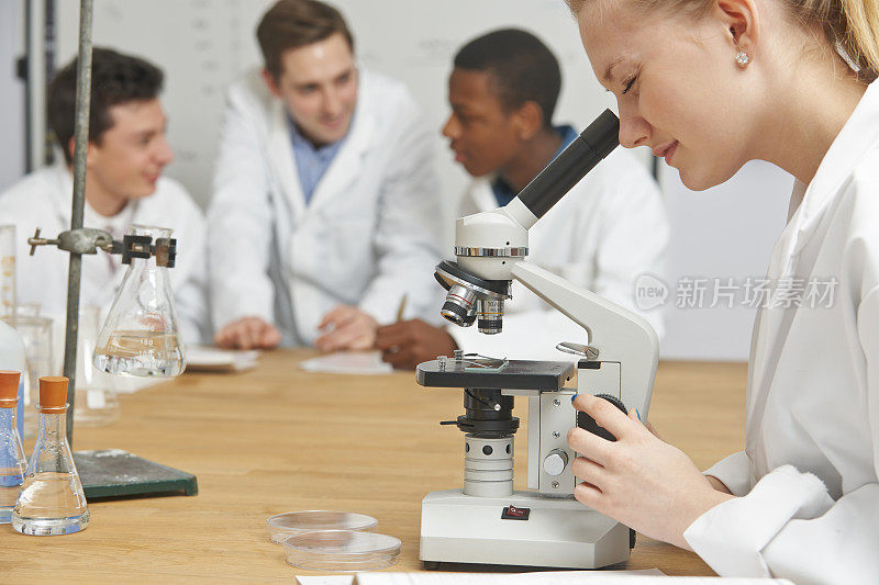 女学生在科学课上使用显微镜