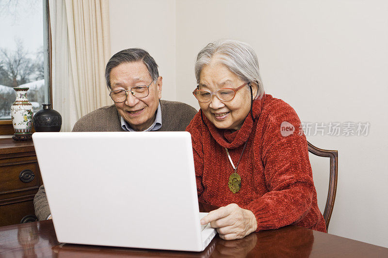 华人亚洲老年夫妇家庭使用笔记本电脑和互联网