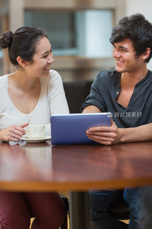 微笑的夫妇在咖啡店里用着他们的平板电脑