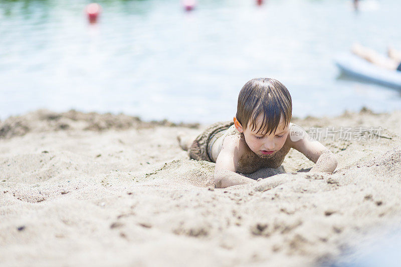 男孩在沙滩游泳后挖沙子