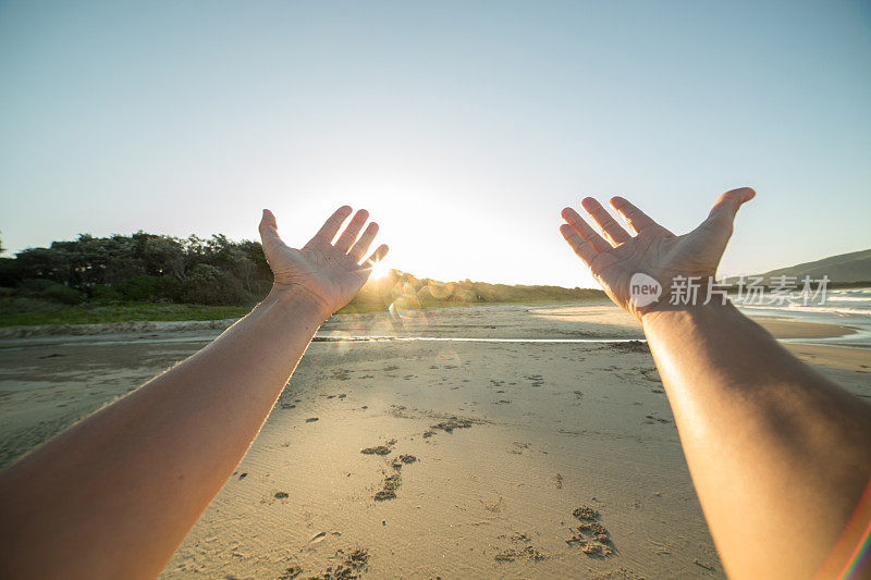 女性向夕阳伸出手臂的个人视角