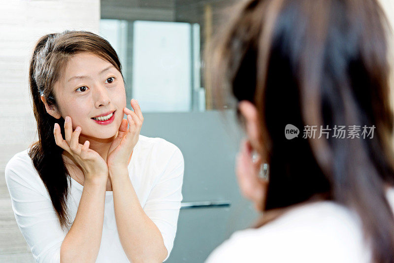 漂亮的年轻女子在镜子前自我欣赏