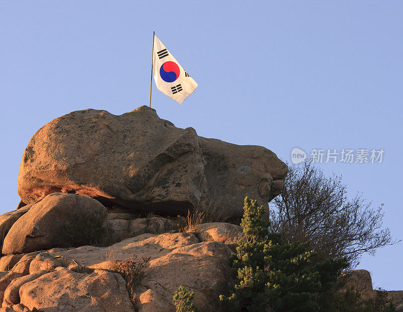 在岩石的山顶上悬挂着一面韩国国旗