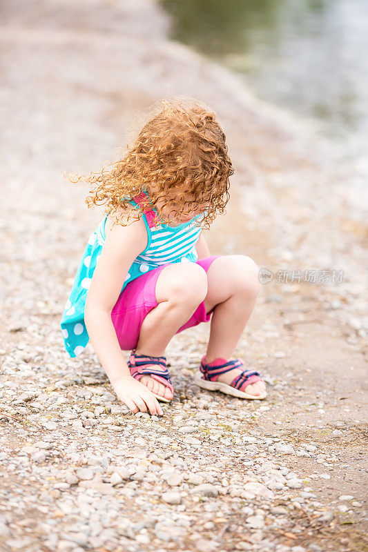 小女孩在河岸上捡石头