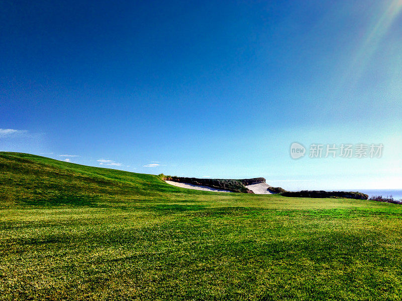 蓝天映衬下的高尔夫球场球道和沙坑