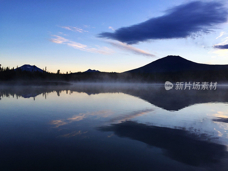 黎明时群山倒映在平静的湖面上