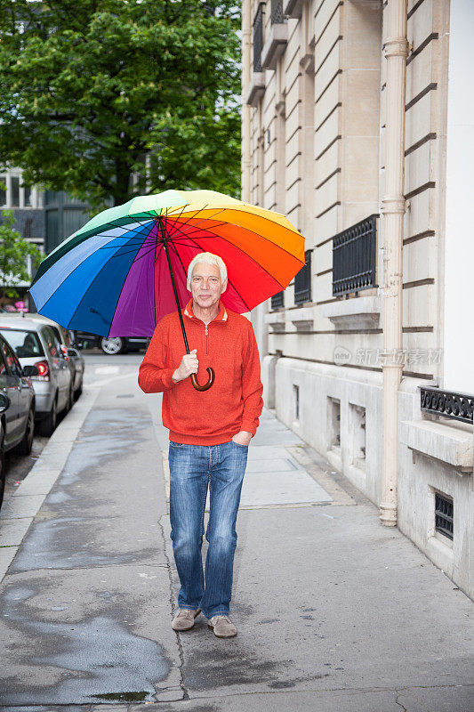 快乐的老年漫步在彩虹伞下的巴黎
