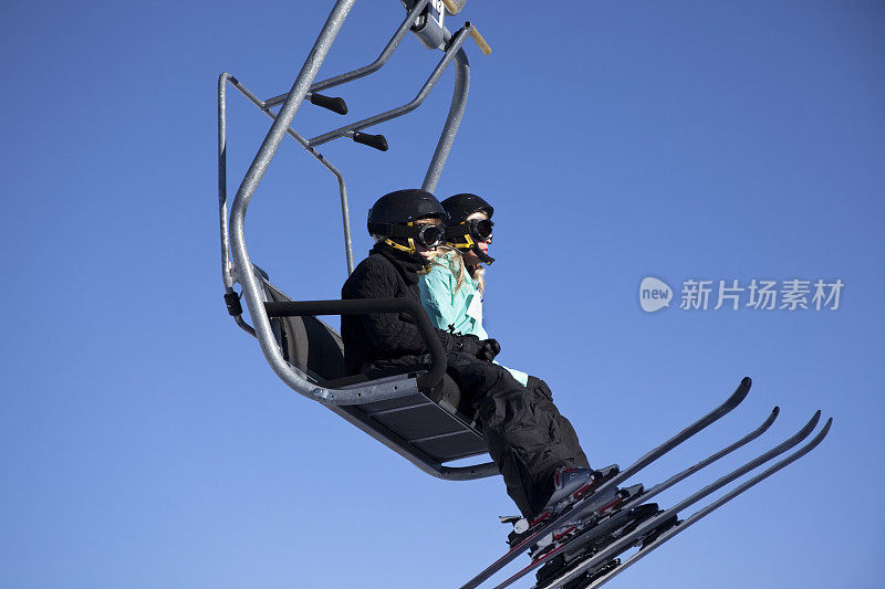 两名滑雪者在蓝天背景下滑雪