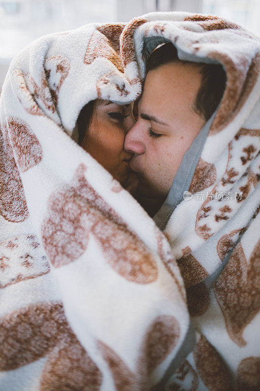 年轻多情的情侣在毯子下接吻