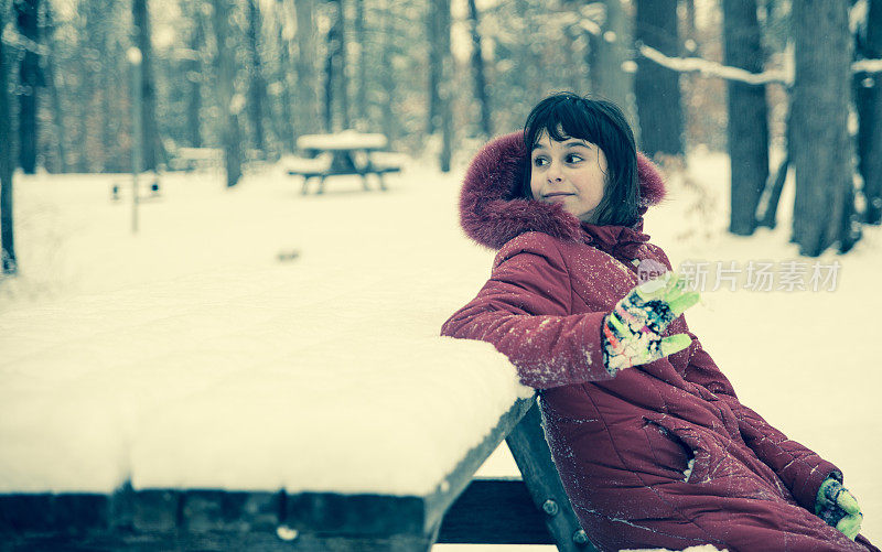 在冬天的森林里，女孩坐在公园的长椅上