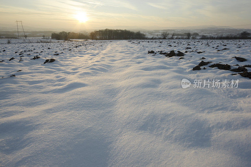 冬日日落时，田野上覆盖着白雪