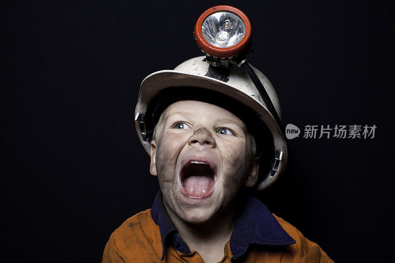 小男孩戴着矿工安全帽，穿着安全服