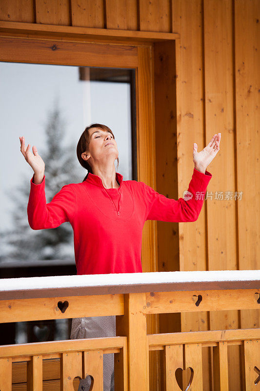 阳台上的一个女人正伸开双臂，手里拿着雪
