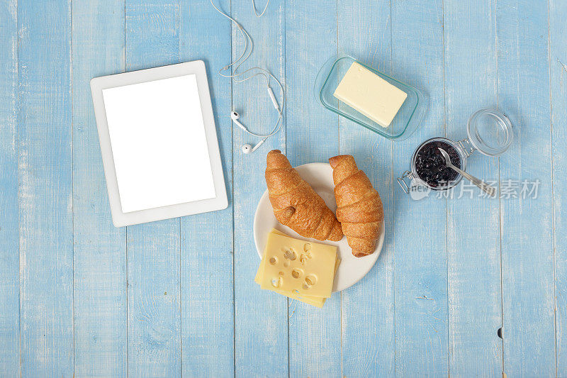 白色平板在家庭厨房与牛角面包，果酱，奶酪，黄油和咖啡，俯视图。早餐桌上的概念