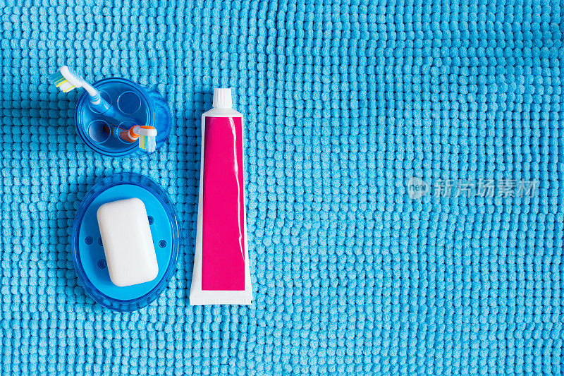 带牙刷的蓝色玻璃，牙膏管和带白色肥皂的肥皂盒。