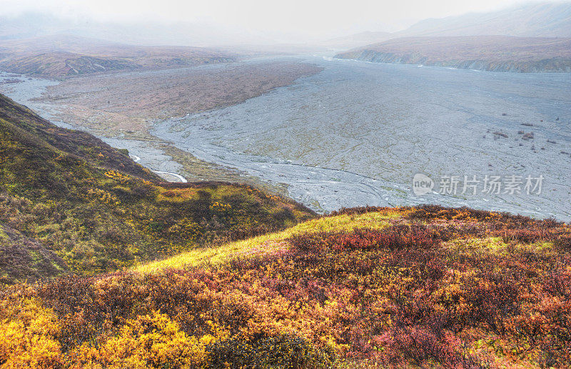 秋天，阿拉斯加一条缓慢的辫状河蜿蜒穿过蓝莓丛覆盖的群山。