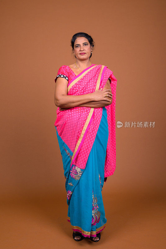工作室拍摄的成熟美丽的印度妇女穿着印度传统服装莎丽在彩色的背景