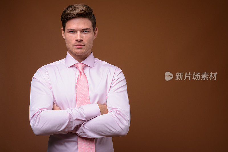 工作室拍摄的年轻英俊的商人穿着粉红色的衬衫和粉红色的领带，以彩色的背景